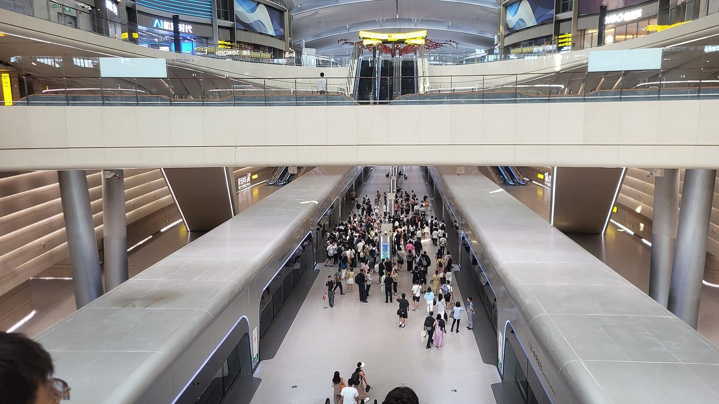 Passengers moving between two trains on a modern underground rail platform in Chongqing.